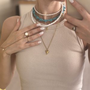 Κολιέ με τιρκουάζ αστερίες και χρυσό μενταγιόν κοχύλι πάνω σε λευκή επιφάνεια – boho καλοκαιρινό κόσμημα